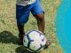 small child kicking soccer ball on grass